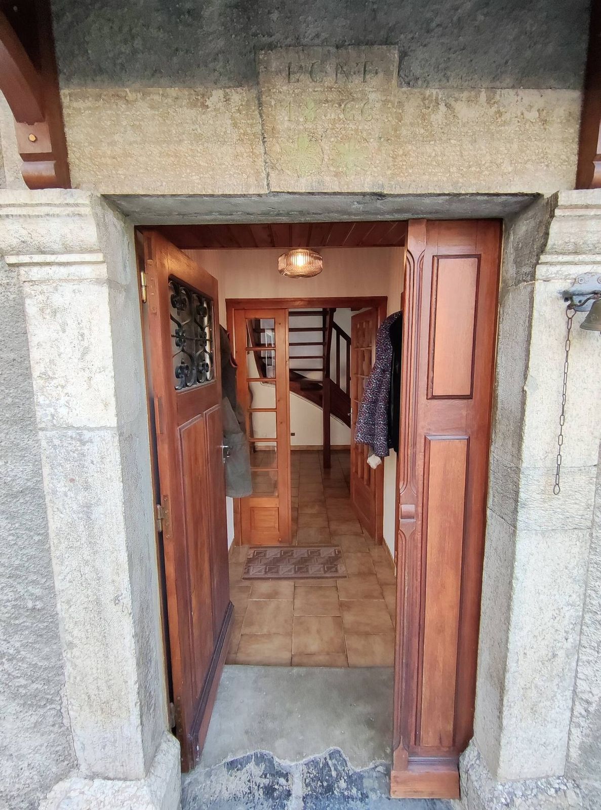 L'entrée de la maison, avec sa porte en bois et sa pierre gravée