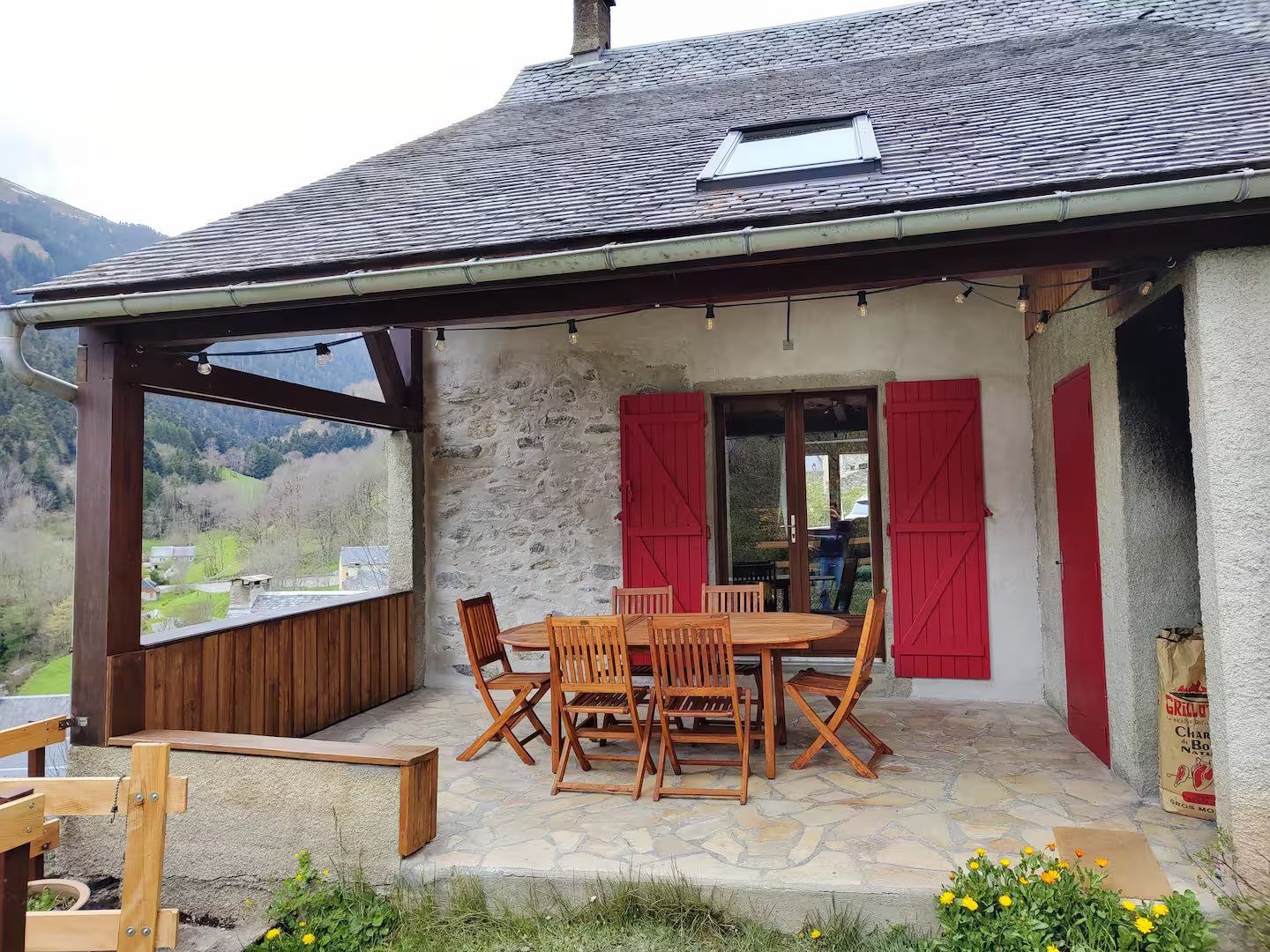 La terrasse sous auvent et ses volets rouges